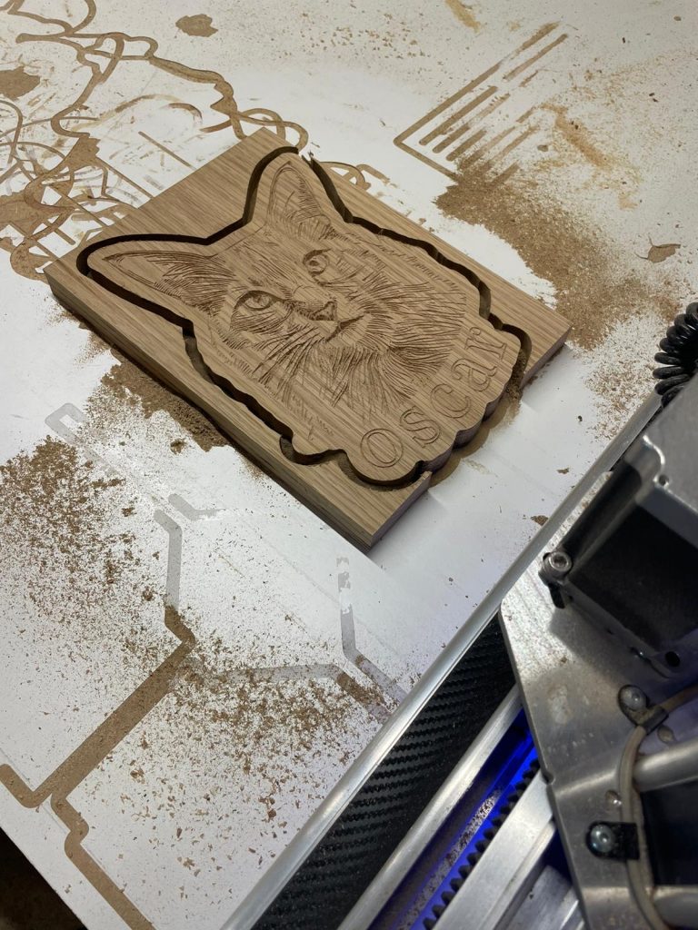 CNC engraving a personalised oak panel with a cat portrait named Oscar — custom wooden pet gift crafted in Cambridgeshire workshop.