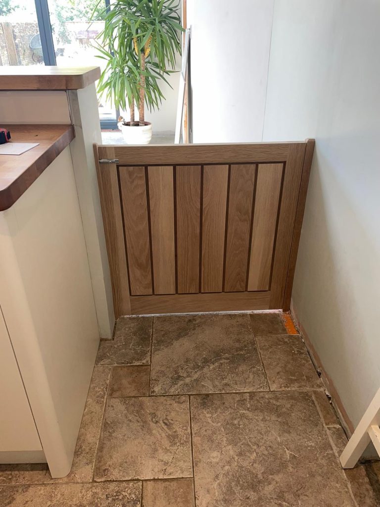 Custom oak dog gate installed in kitchen entrance — bespoke panelled design crafted in Cambridgeshire.