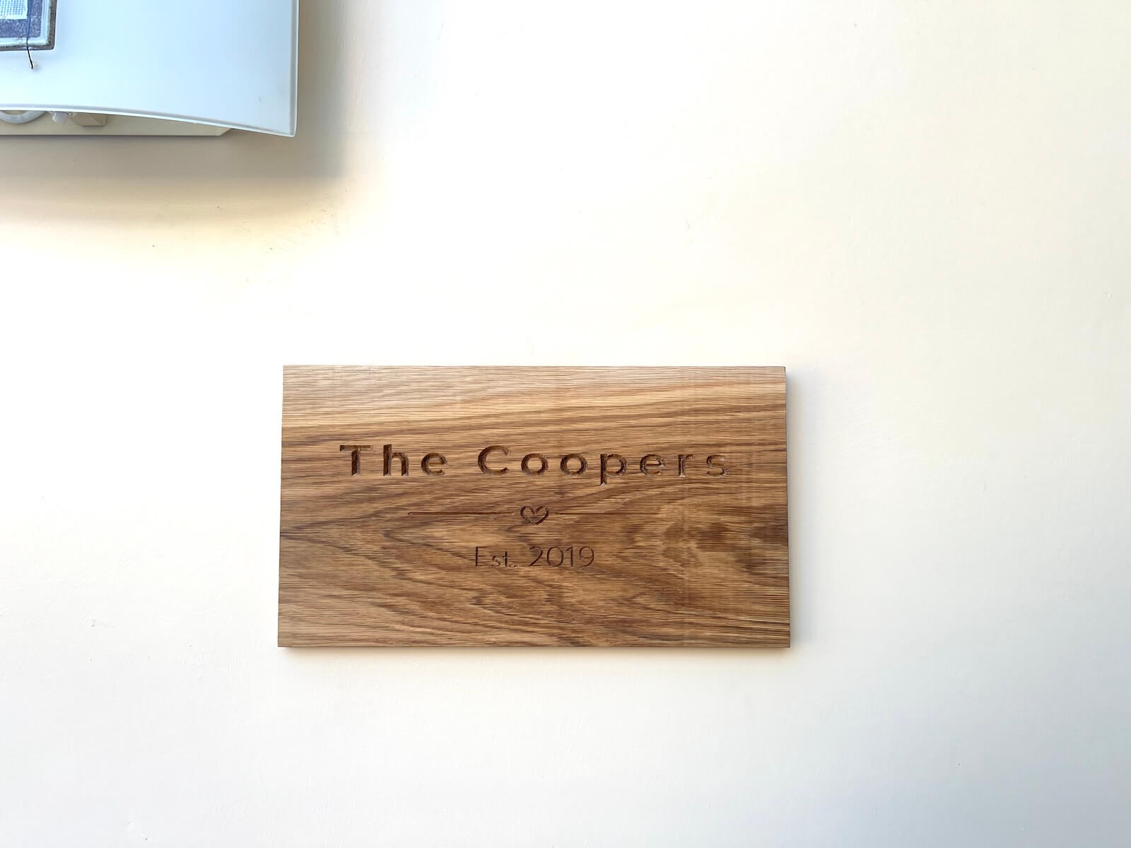 Engraved oak wall plaque personalised with family name hanging on wall.