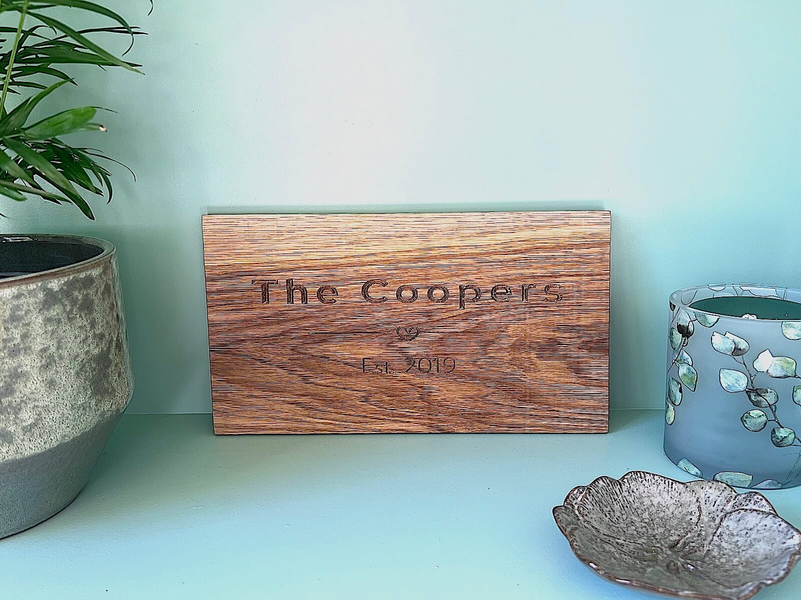 Personalised oak plaque engraved with The Coopers Est. 2019, styled with candles and decor.