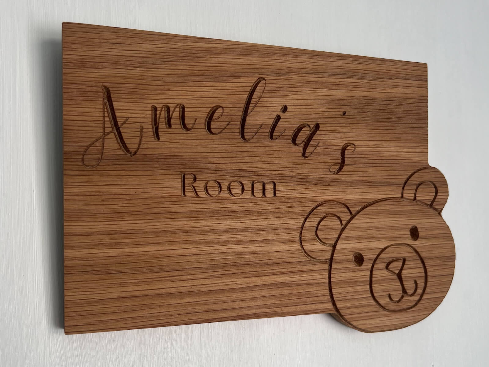 Handmade oak children’s room sign engraved with name and teddy bear detail, wall mounted.