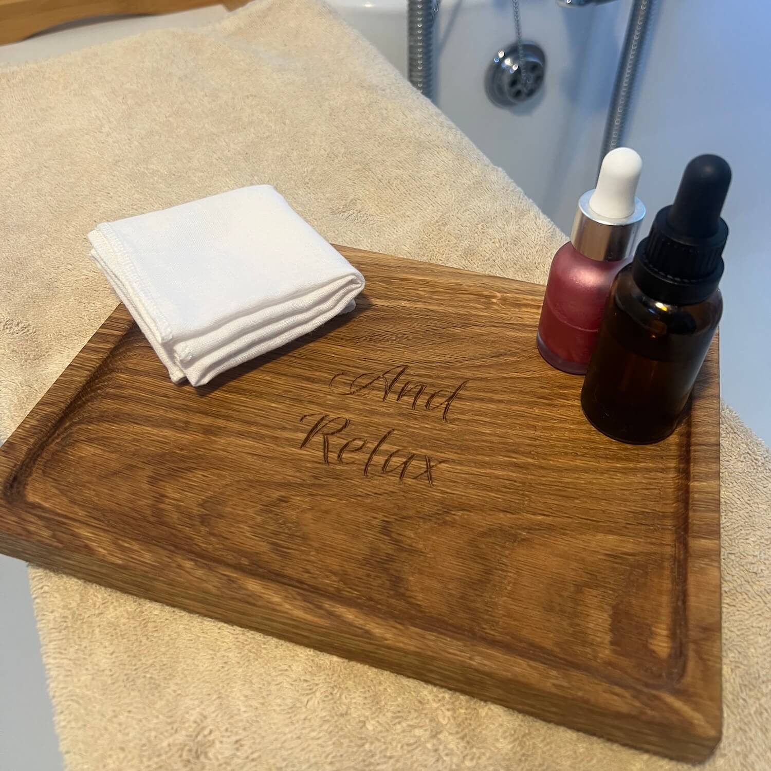 Personalised oak display tray engraved with “And Relax,” styled with skincare bottles and cloth.