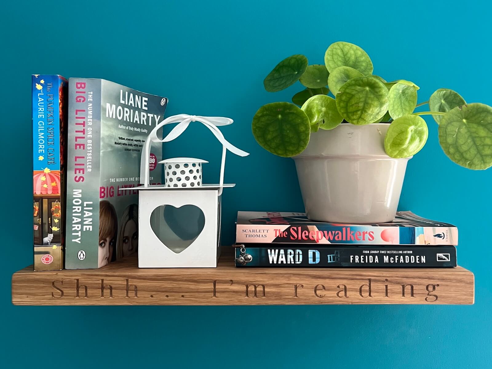 Personalised oak floating shelf with engraved text “Shhh… I’m reading” styled with books, a plant and lantern.
