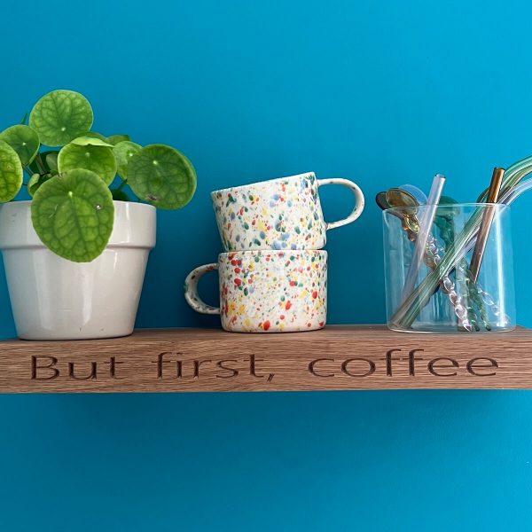 Personalised oak floating shelf engraved with “But first, coffee” styled with mugs and a plant.