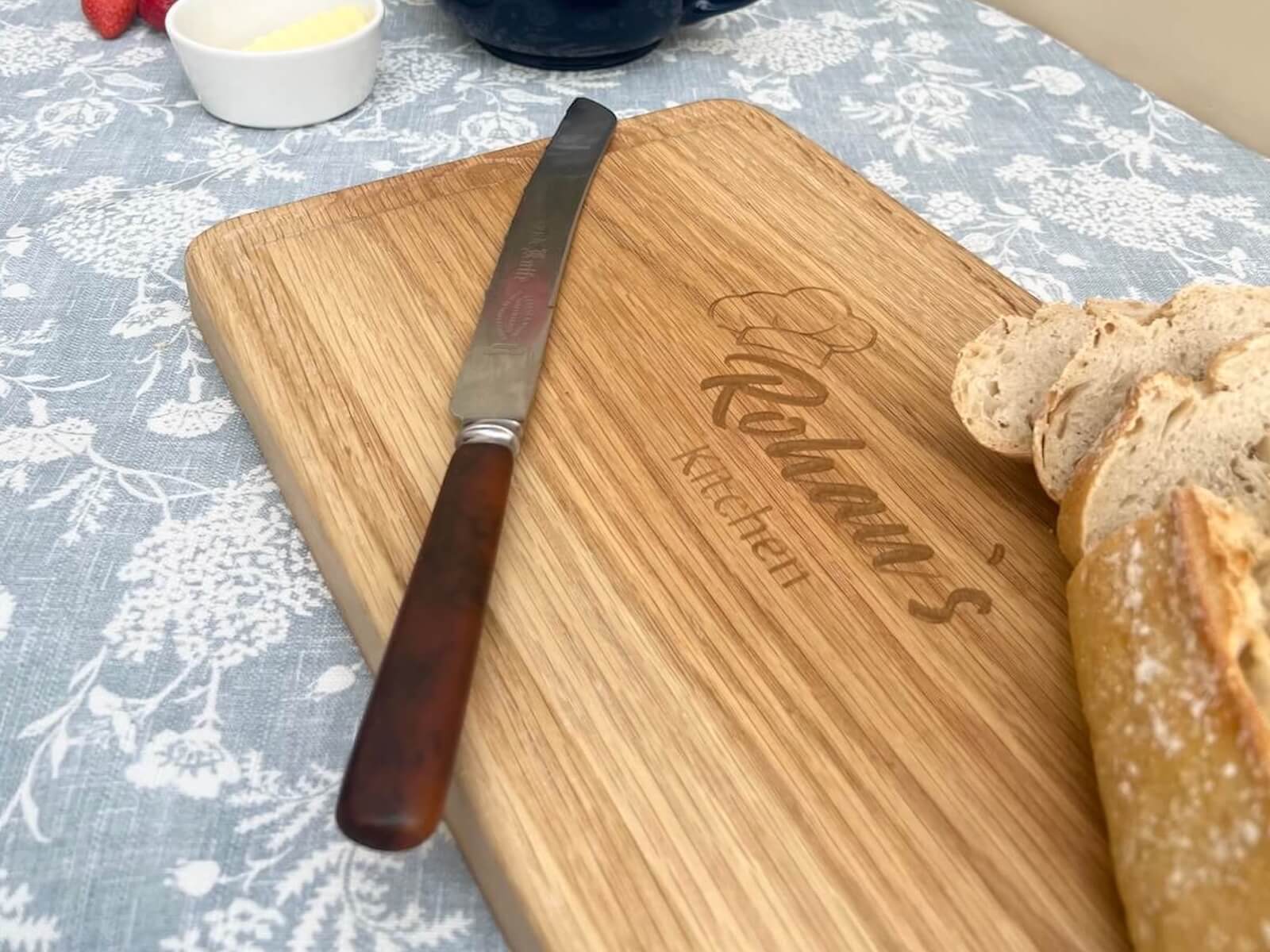 Engraved oak chopping board with bread and knife, handcrafted in Cambridgeshire.