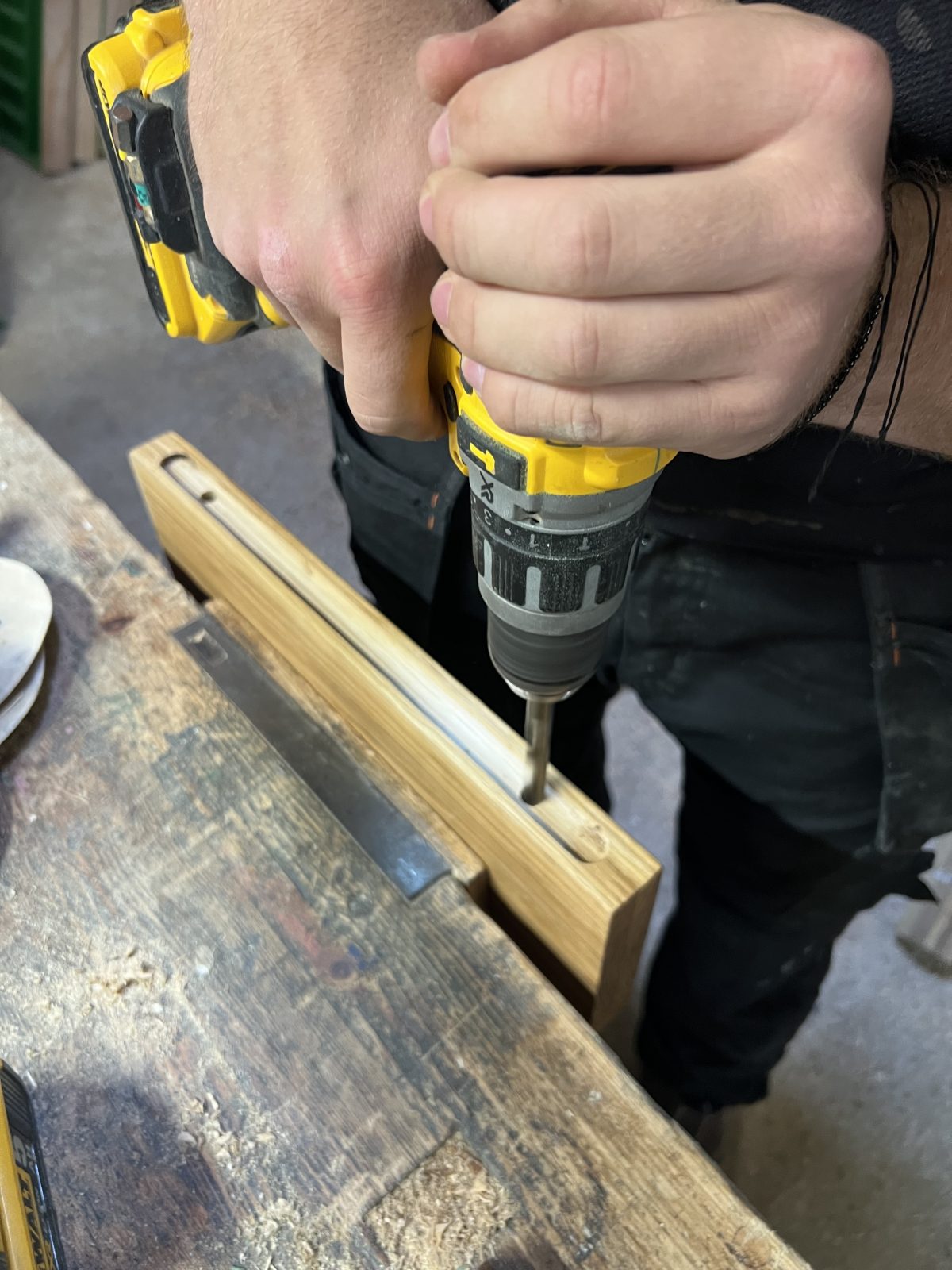 Drilling slot for floating shelf bracket in handmade solid oak shelf with engraved text.