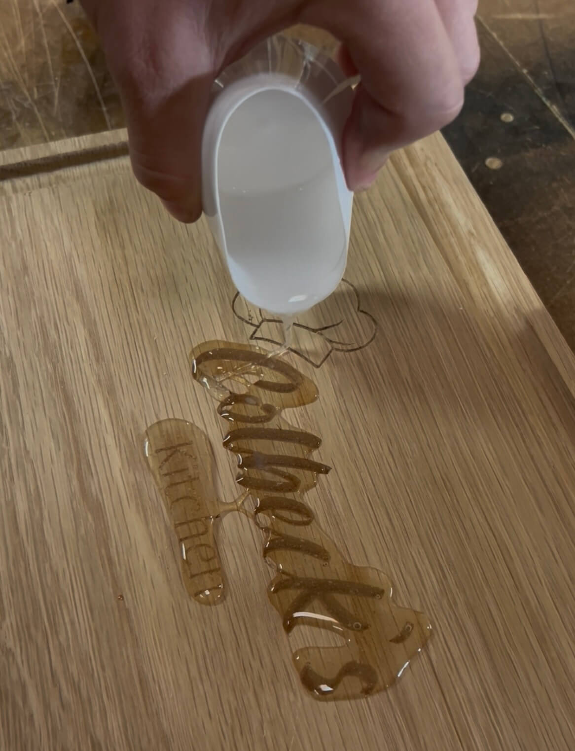 Pouring clear food-safe resin into CNC-engraved oak board for a personalised chopping board.