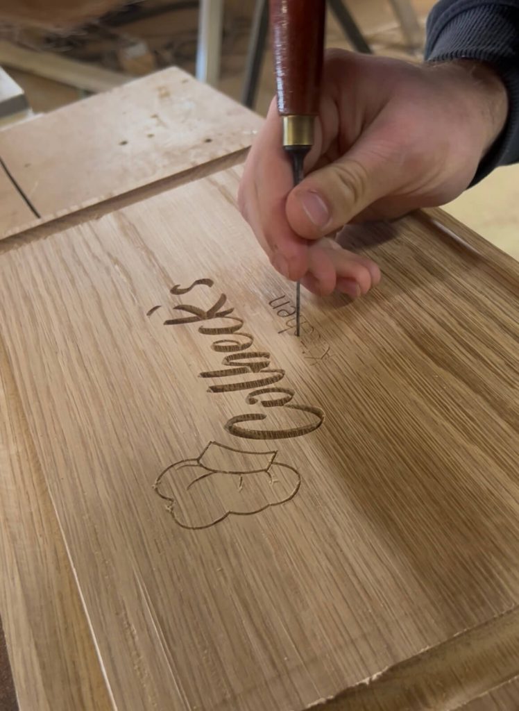 Cleaning the engraved lettering on a personalised oak chopping board before applying resin and finishing.
