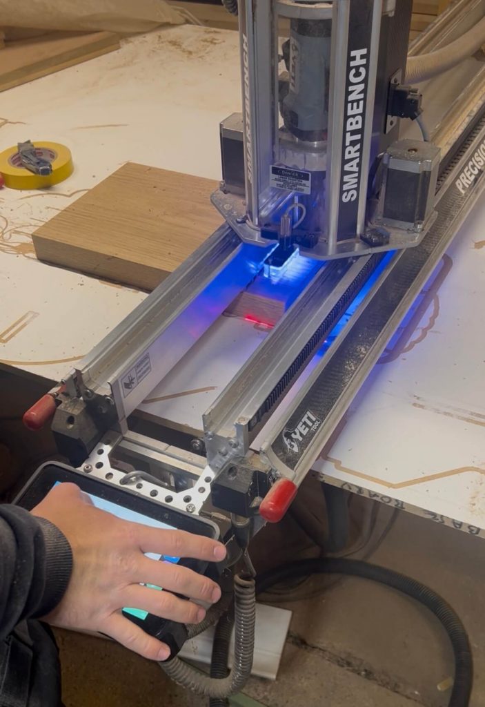 A CNC machine being set up with blue guiding lights to prepare for engraving a personalised oak chopping board.