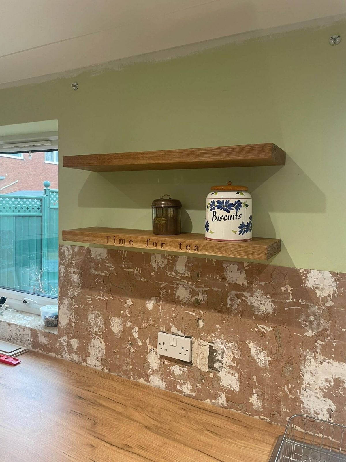 Installed pair of bespoke oak floating shelves, including a personalised CNC-engraved ‘Time for tea’ shelf, crafted and fitted as part of a custom kitchen project in Cambridgeshire.