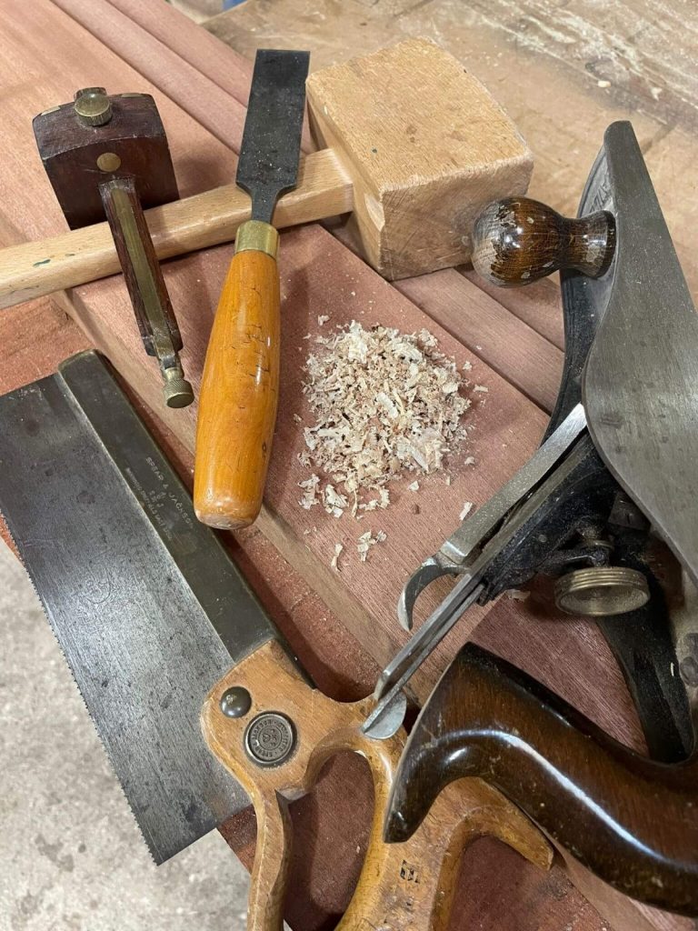 Close-up of traditional woodworking tools and wood shavings on a workbench — custom carpentry craftsmanship.