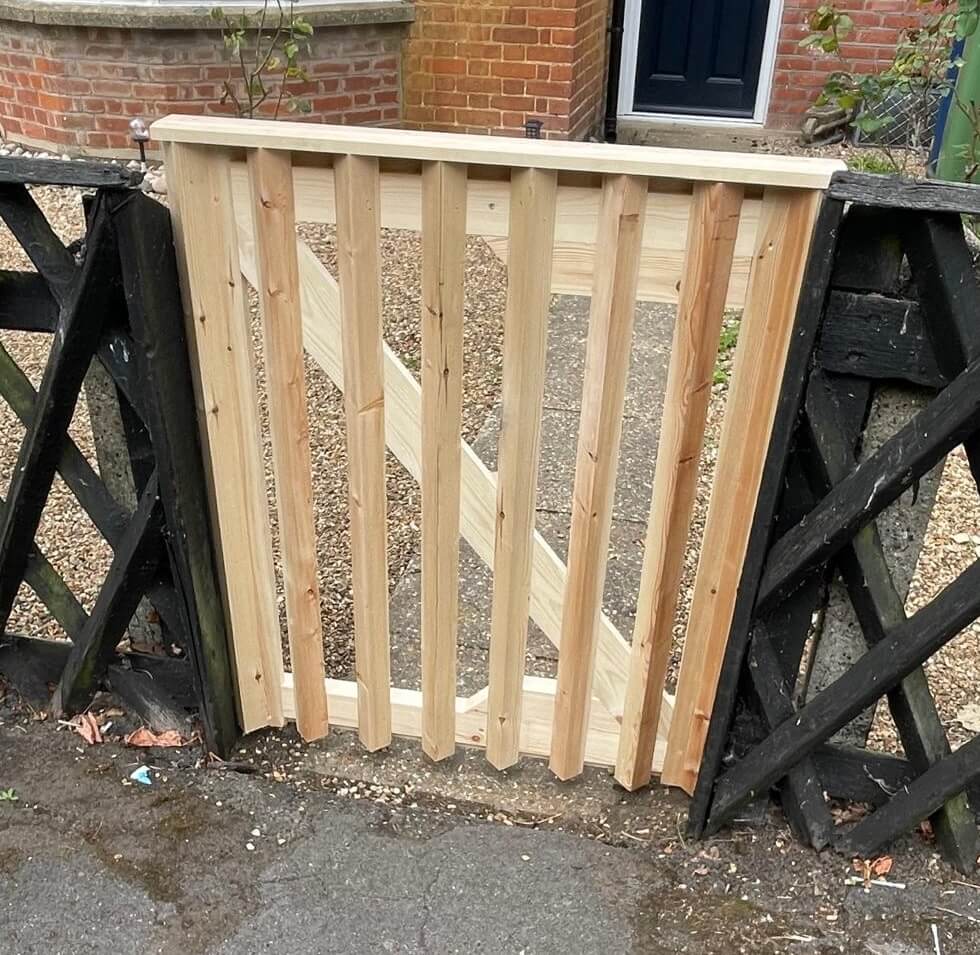 Custom softwood gate installation showing vertical slats and bracing, crafted by KMP Carpentry & Joinery as part of a front-garden improvement project in Cambridgeshire.