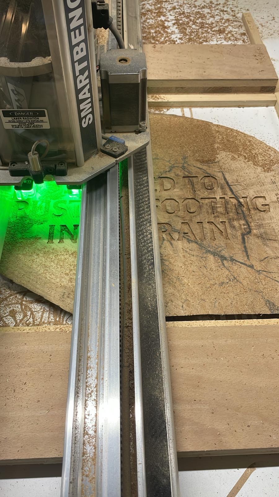 CNC router engraving custom text into a live edge oak slab secured for accurate cutting.