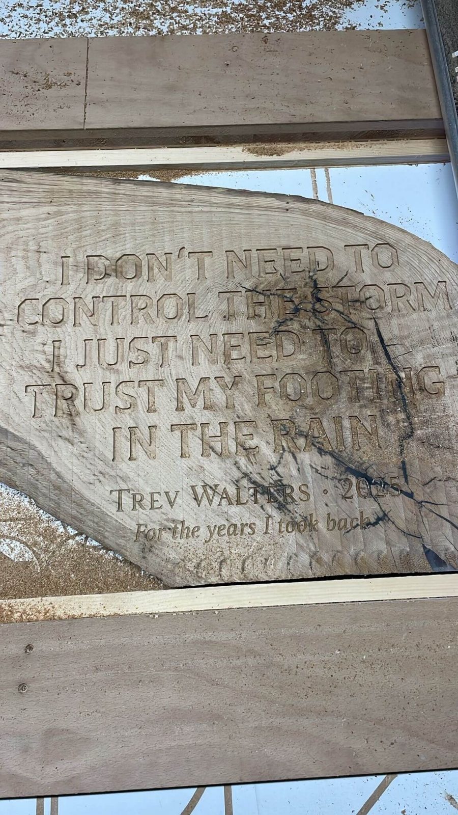Freshly CNC engraved lettering in live edge oak slab before black epoxy resin infill.