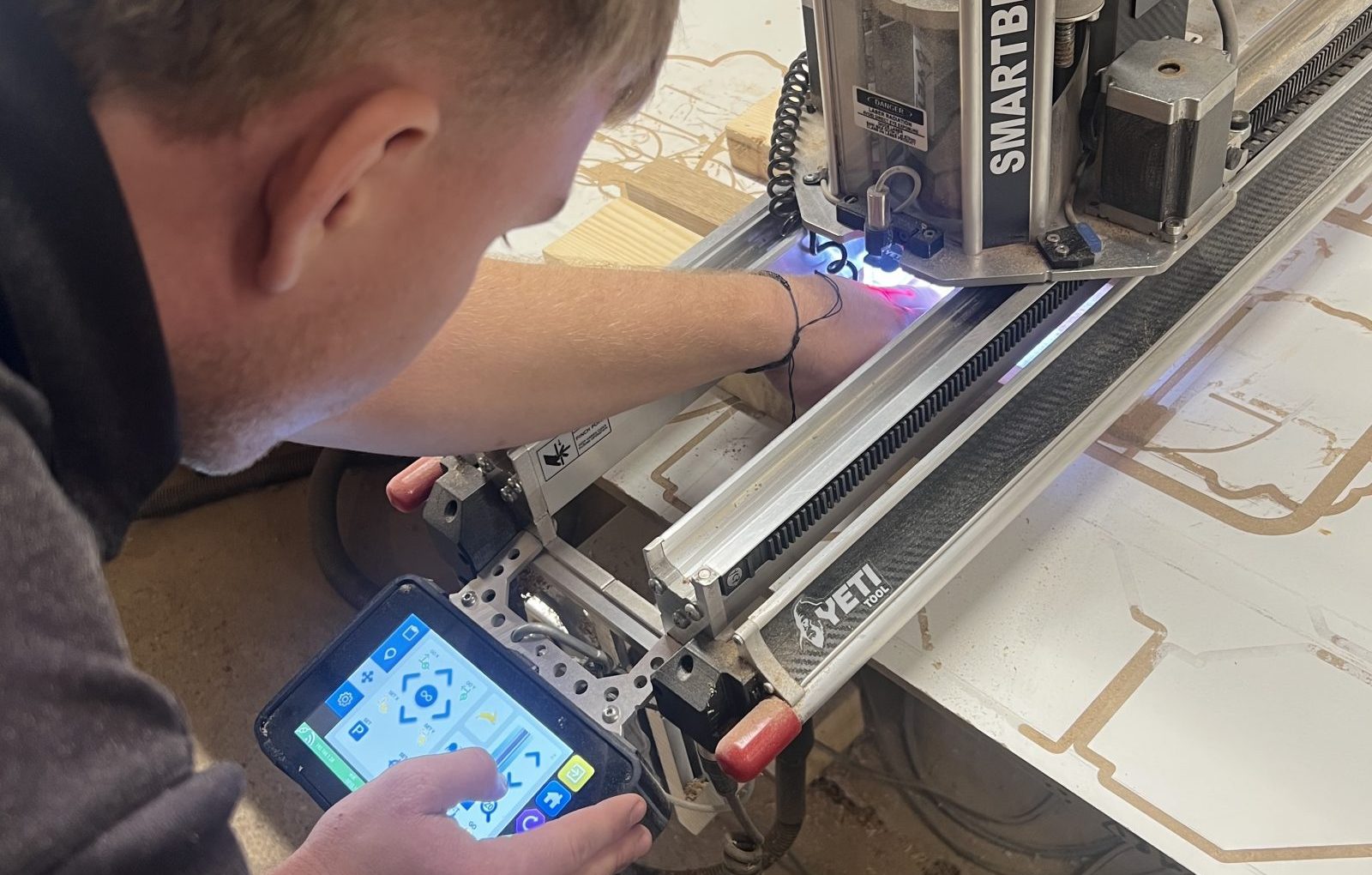 CNC machine operator setting up precision timber components for trade CNC machining project.