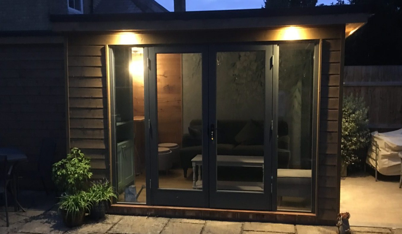 Finished timber garden room in Cambridgeshire with glazed patio doors and exterior lighting.