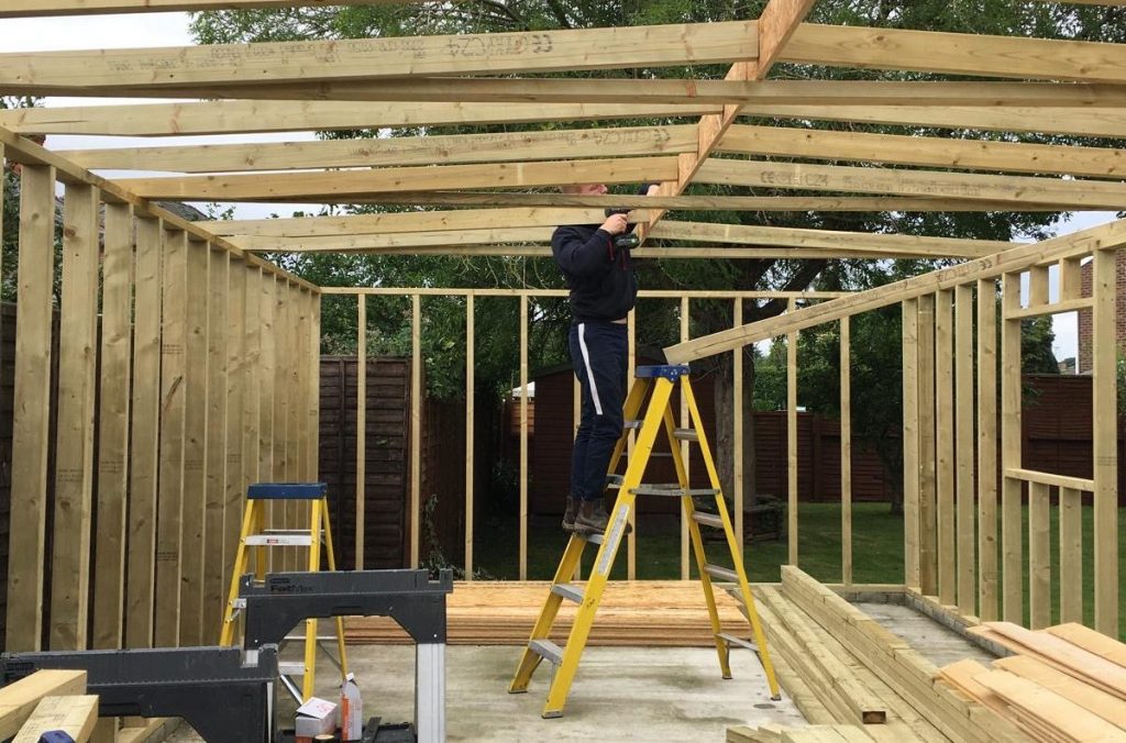Timber frame extension under construction in Cambridgeshire with structural roof beams being installed.
