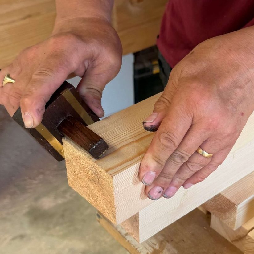 Joiner marking out a traditional mortise and tenon joint by hand in a joinery workshop.