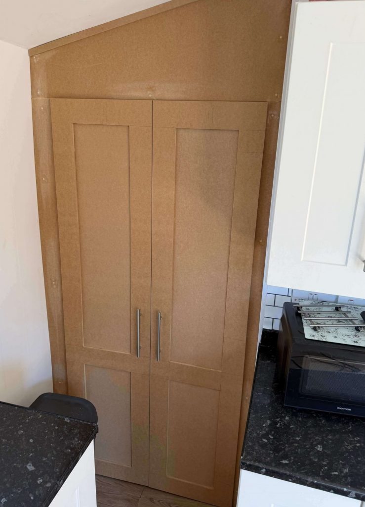 Fitted cupboard built into kitchen space for storage.