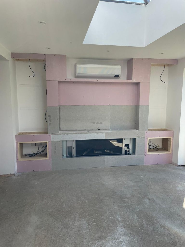 Fire rated media wall structure with plasterboard and fireplace recess installed.