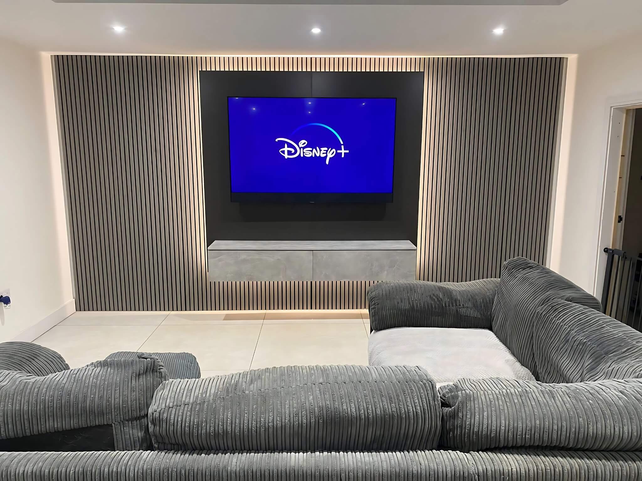 Slatted media wall with mounted TV and ambient lighting in a living room.