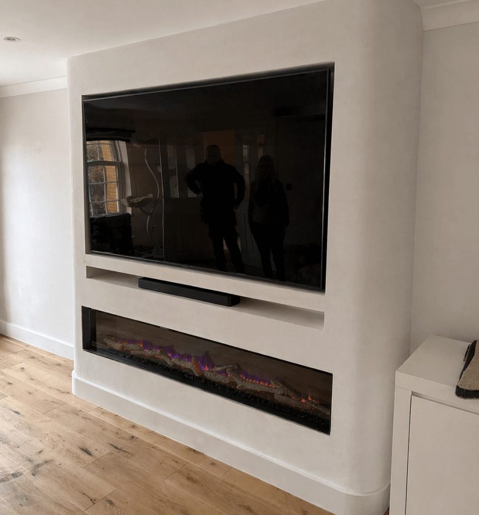 Modern media wall with built-in TV and fireplace designed by a media wall carpenter.