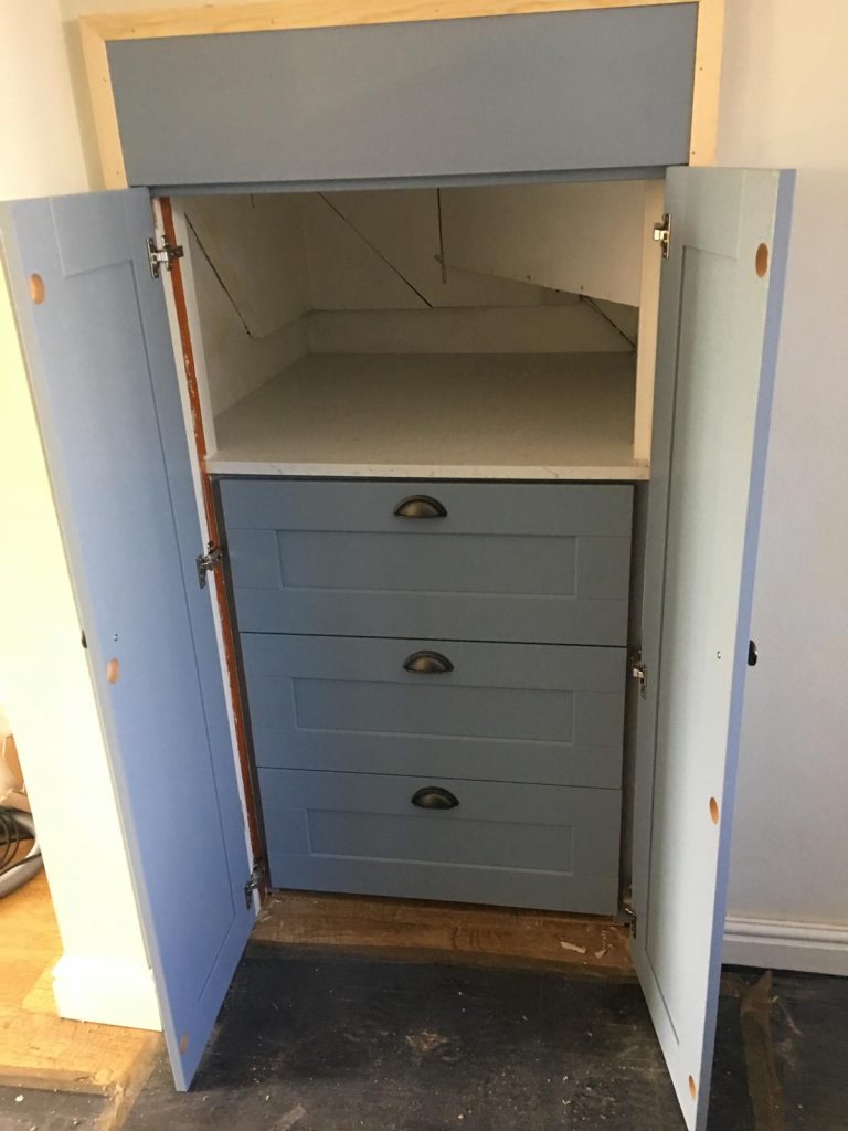 Built-in cupboard with drawers open showing internal storage space.