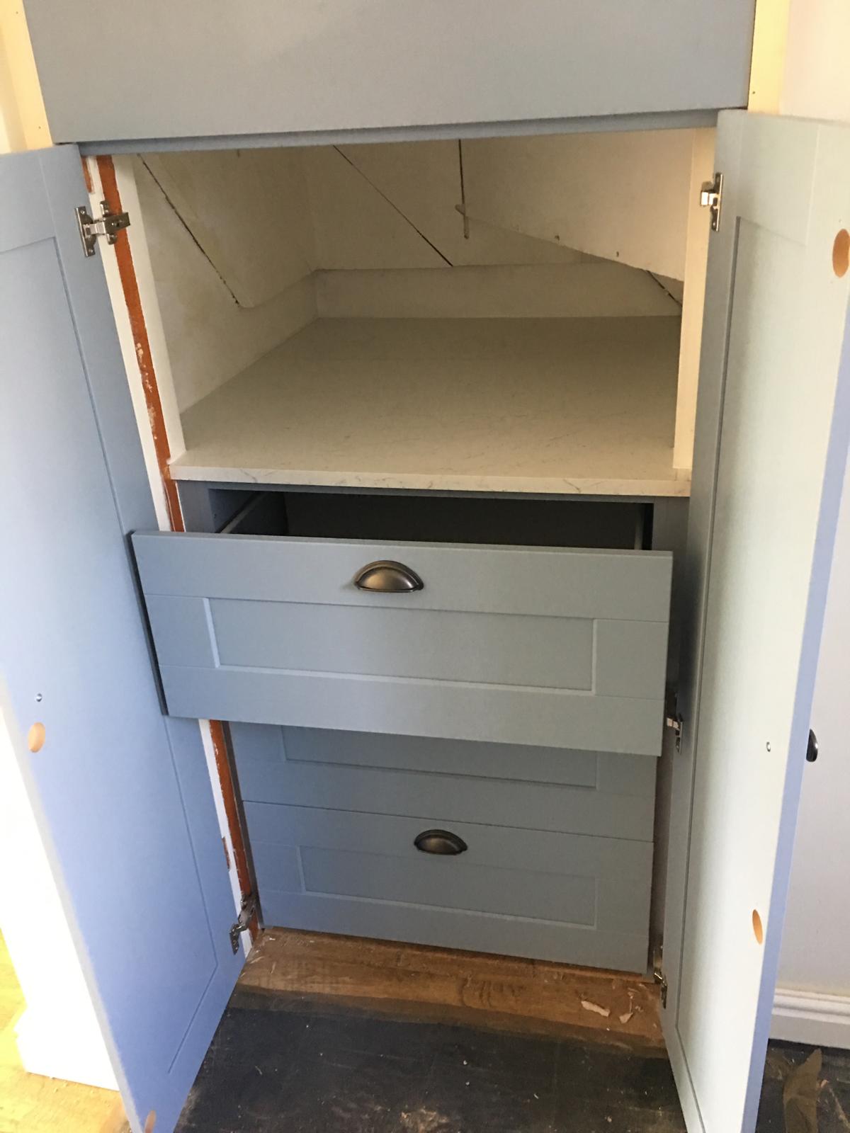 Close-up of fitted storage drawers inside alcove cupboard.