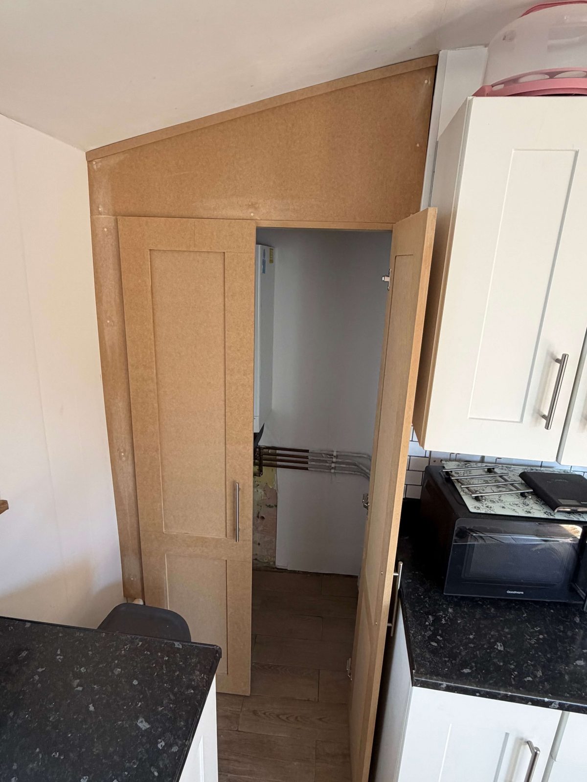 Built-in alcove storage cupboard with door open showing hidden boiler space.