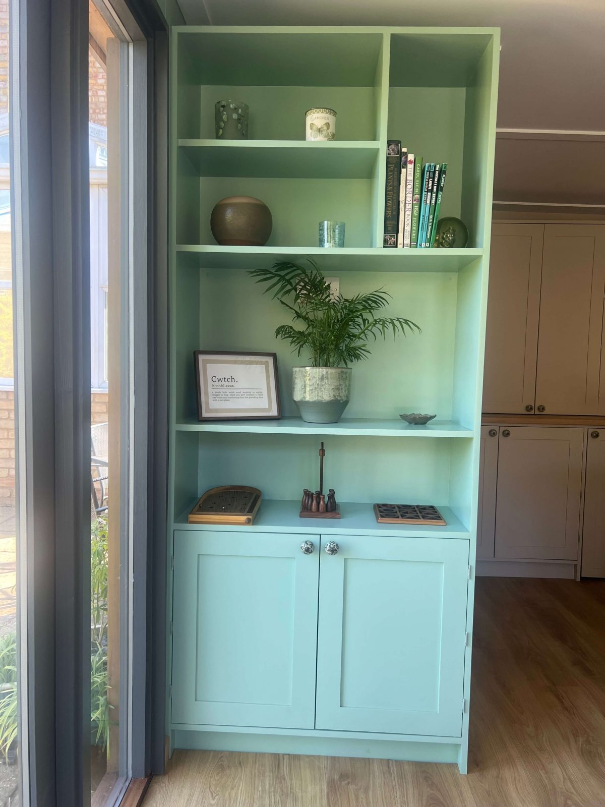 Fitted garden room shelving with cupboard storage and decorative display.