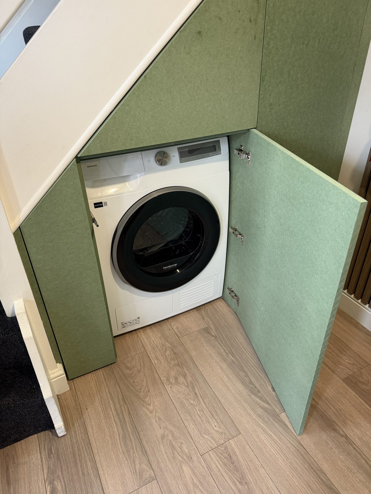 Understairs storage with washing machine housing and fitted cupboard doors.
