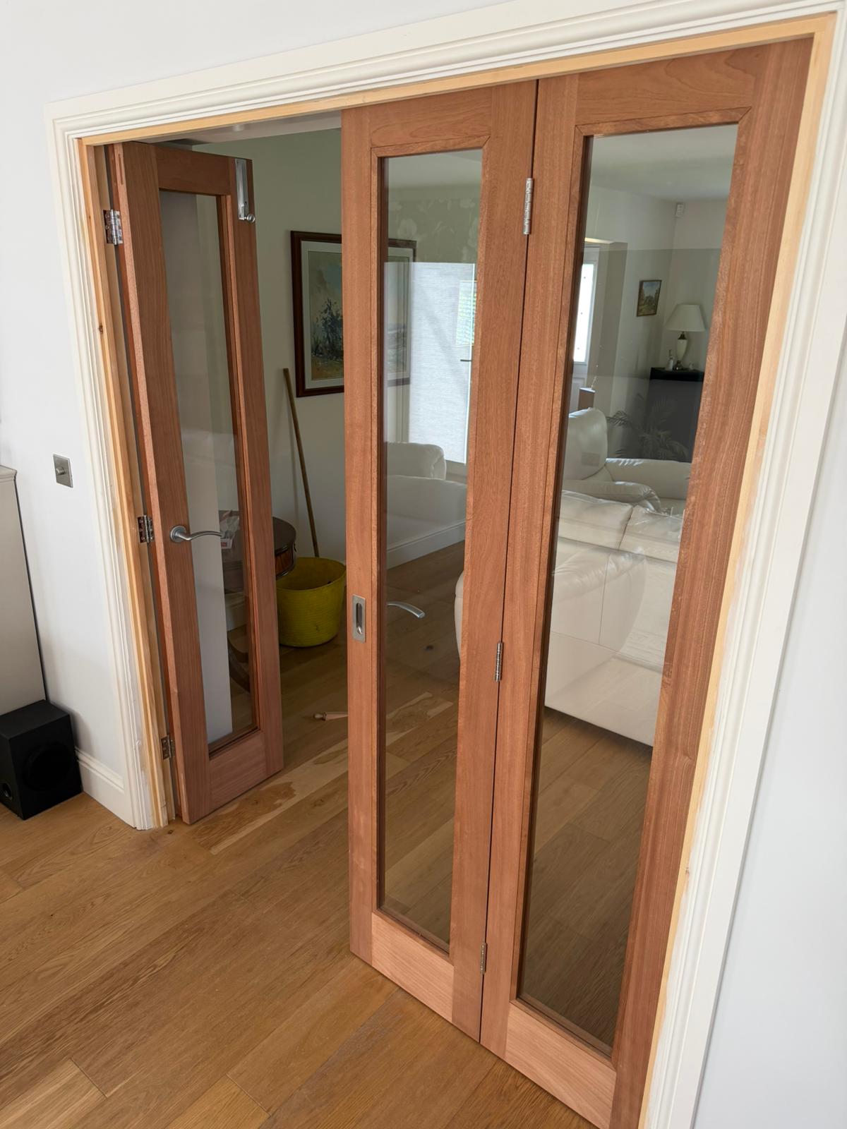 Finished bespoke sapele bi-fold doors open between the kitchen and lounge in a Cambridgeshire home.